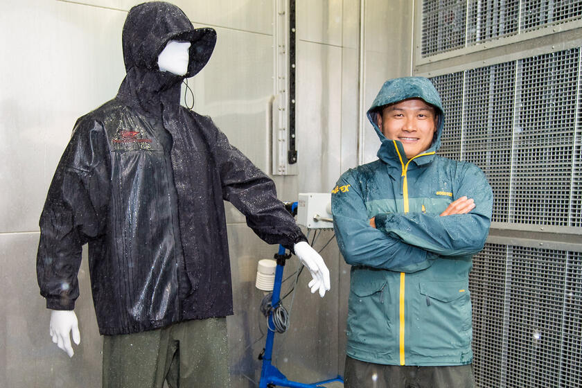 Man testing the waterproof features of a garment in the rain room